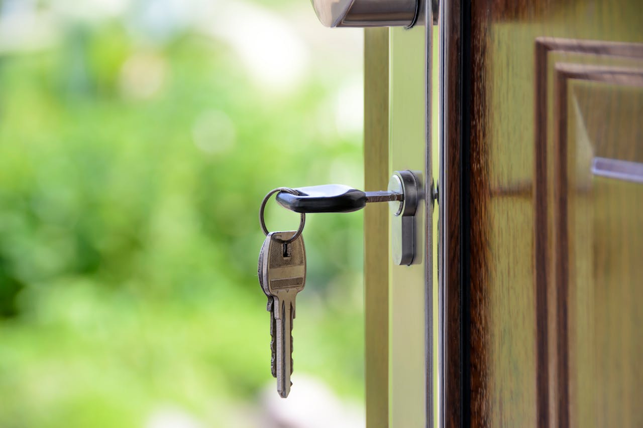 about-img-01 Key inserted in door lock against a blurred green background, symbolizing security and real estate.