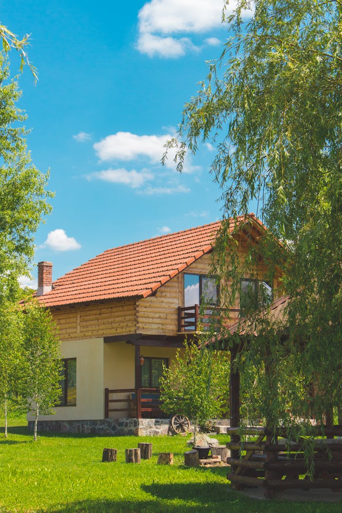 our-story Discover a picturesque rustic house surrounded by vibrant greenery in a serene summer landscape.