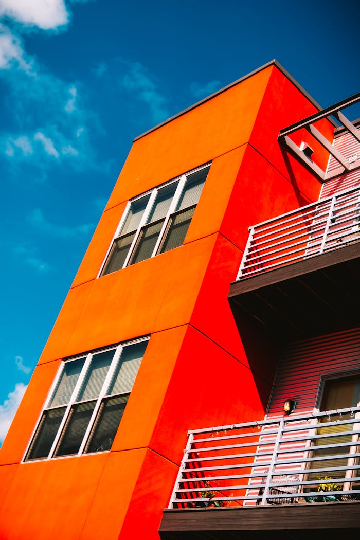 gallery-05 Low angle of a vibrant orange modern apartment building against a bright blue sky in Eau Claire.