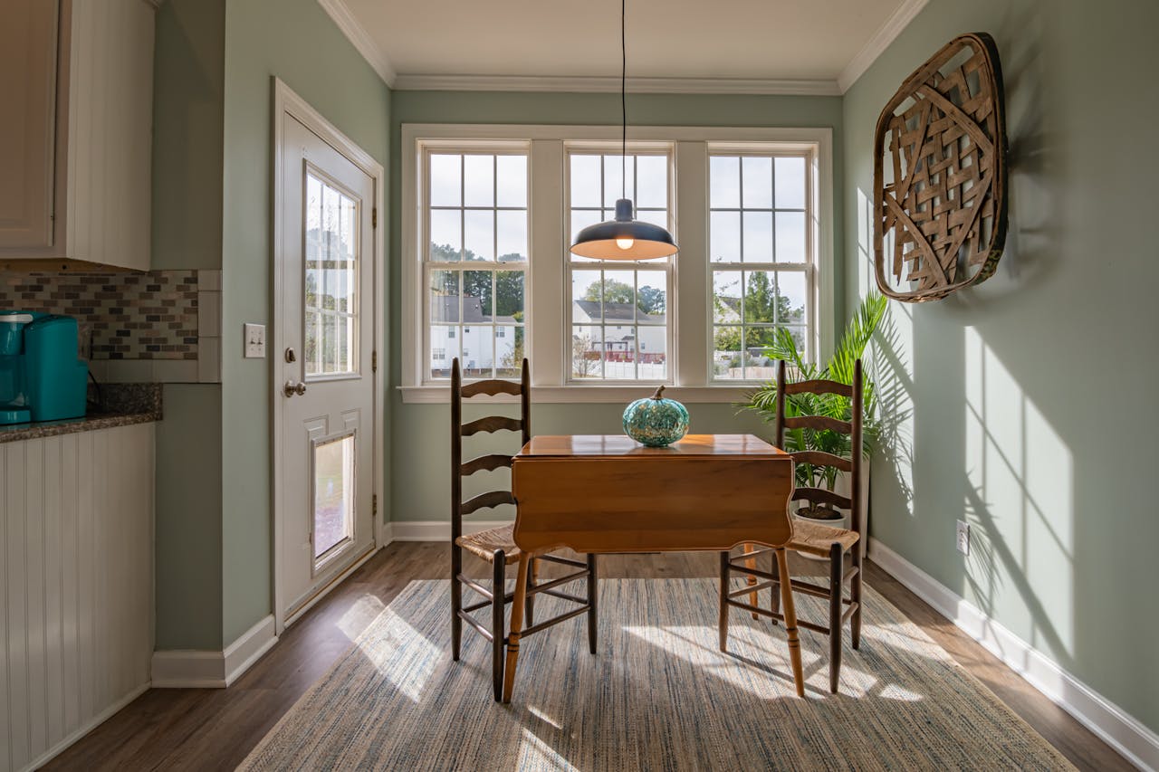 home-img Bright dining area with wooden furniture and large windows showcasing natural light.